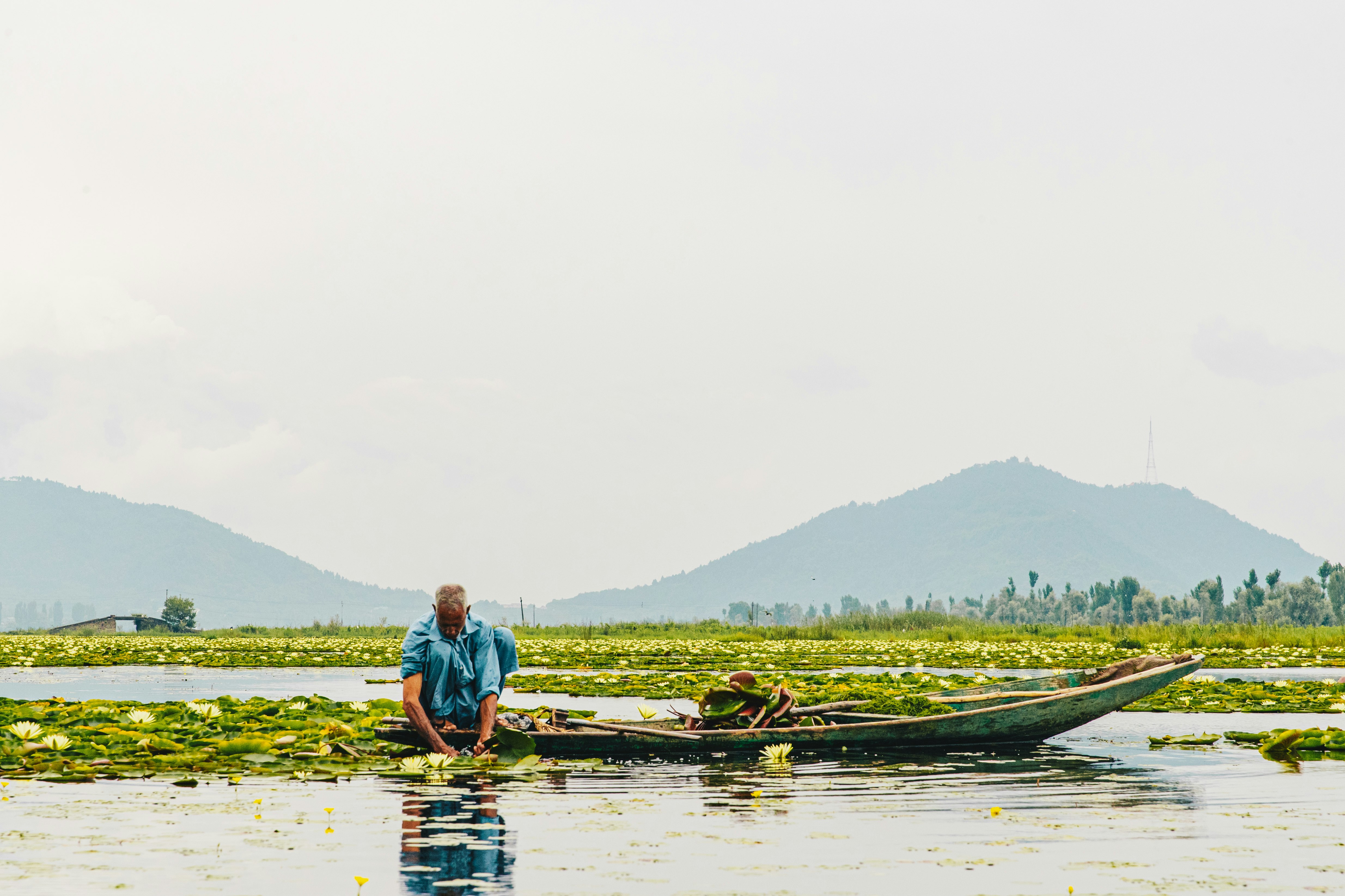 man in blue shirt riding on boat on lake during daytime